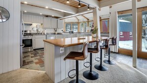 Une cuisine moderne avec des meubles blancs, un îlot central en bois et des tabourets de bar.