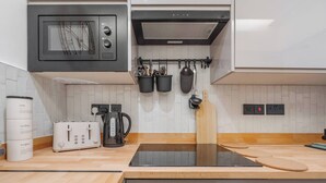 A modern kitchen with a built-in microwave, kettle, and toaster. There are cabinets, a wooden countertop, and a dishwasher. - Near Anfield | SofaBed & Mini Fridge | Parking (Liverpool)