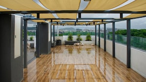 A covered outdoor area with a wooden floor, potted plants, and a view of a cityscape. - Cozy studio in marvelous Pune with AC, WiFi, Yashvantgad. (Pune)