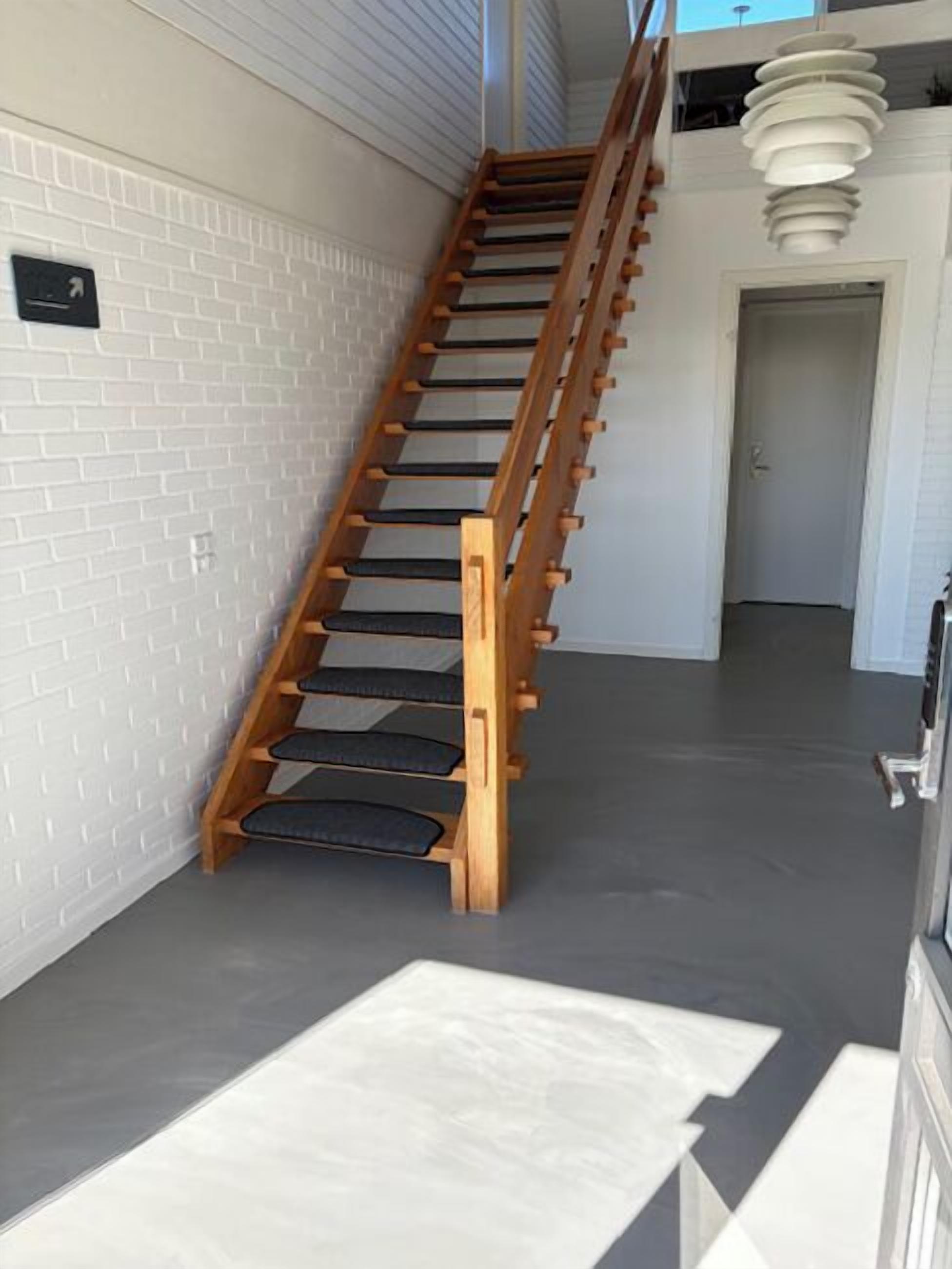 A wooden staircase with black steps leading to a second floor.