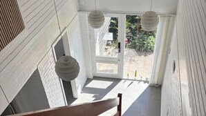 Eine Treppe mit Holzboden und Handlauf, die zu einer Tür mit Blick auf Grünfläche führt.