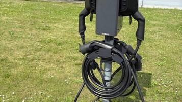 An outdoor electrical box with cables on a grassy area.