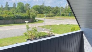 Ein Balkon mit Blick auf eine Straße und Grünflächen.
