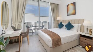 Een hotelkamer met een bed, bureau, stoel en een balkon met uitzicht op de lucht.