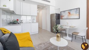 Een moderne keuken met witte kasten, een roestvrijstalen koelkast en een eethoek met een witte tafel en stoelen.