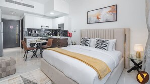 Een moderne hotelkamer met een groot bed, een zithoek en een kitchenette.
