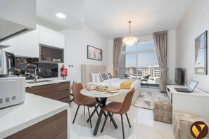 Relax in a spacious room with a large bed, dining area, and kitchenette, offering a city view from the balcony.