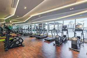 Une salle de sport équipée de tapis de course, de vélos elliptiques et d’appareils de musculation.
