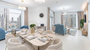 Un comedor moderno con una mesa grande dispuesta para seis personas, un sofá y un televisor montado en la pared.