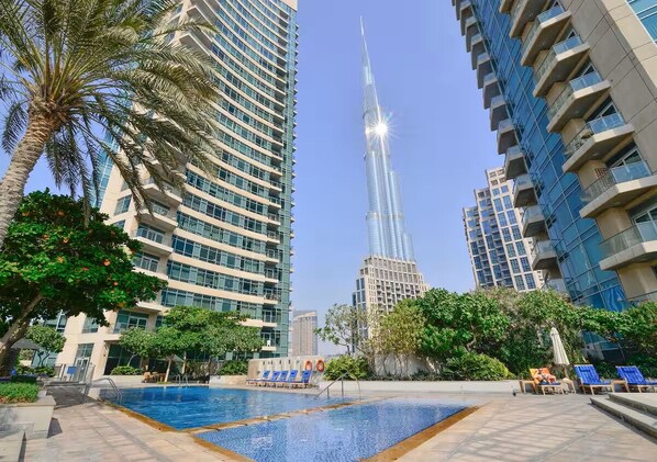 A modern hotel with a pool area, surrounded by tall buildings and palm trees. - Vogue, Downtown The Lofts East near Burj Khalifa and Dubai Mall (Dubai)