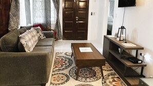 A living room with a sofa, a coffee table, a TV, and a patterned rug.