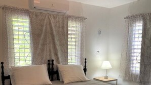 A bedroom with a bed, two bedside tables, a lamp, and a window with curtains.