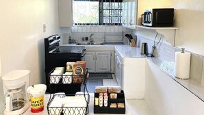 A compact kitchen with white cabinets, a microwave, and a coffee maker.