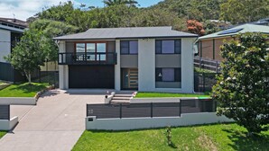 A modern two-story house with a garage, a balcony, and a view of a hilly landscape. - Coastal Bliss Studio at Shoal Bay (Shoal Bay)