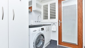 A compact laundry room with a Bosch washing machine, wooden door, and white cabinetry.