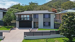 A modern two-story house with a garage, a balcony, and a well-maintained lawn.
