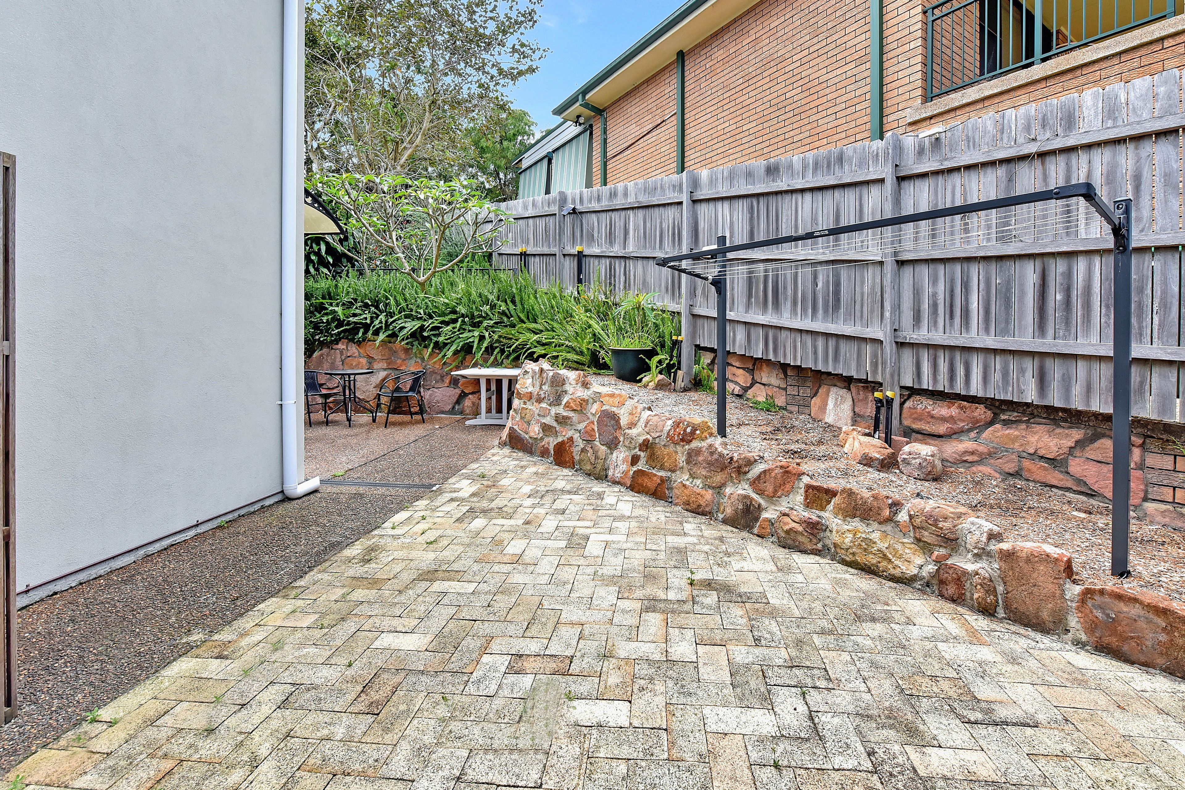 A paved patio with stone walls and a wooden fence.