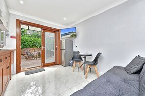 Een compacte woonruimte met een kitchenette, een eethoek en een zithoek met een bank en stoelen.