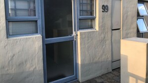 En byggnadsfasad med en dörr, två fönster med persienner och siffran 99.