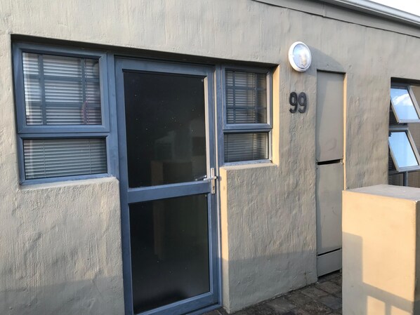 A building facade with a door, two windows with blinds, and the number 99.