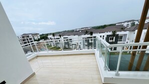 Un balcón con vistas a edificios residenciales, suelo de baldosas y baranda blanca.