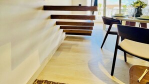 Un interior moderno con una escalera, un comedor y vistas al exterior.