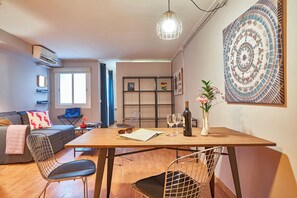 Un salon moderne avec une table à manger en bois, des chaises en métal, un canapé et une bibliothèque.