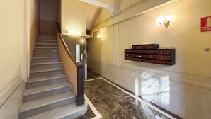 A staircase with a handrail, a wall-mounted light fixture, and a fire extinguisher sign.