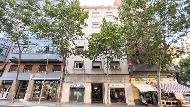 A street view with a building featuring a storefront with a sign for 'Optic Guinardó' and another sign for 'Chef Works'.