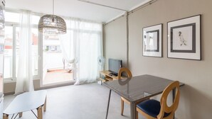 A modern, well-lit room with a dining table, chairs, a TV, and artwork on the walls. - Valles Atico · One bedroom apartment with terrace (Barcelona)