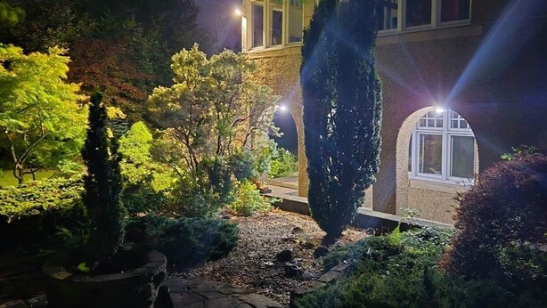 Un jardín bien iluminado con un sendero de piedra que conduce a un edificio con varias ventanas.