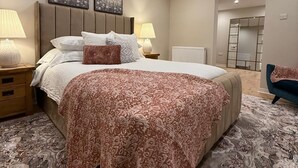 Un dormitorio con una cama grande, dos mesitas de noche, un tocador y un espejo.