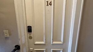 A white door with the number 14, a doorbell, and a handrail. - Downtown Historical 1 Bed Apt (Bay City)