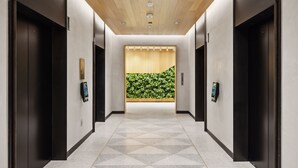 A modern hallway with a geometric patterned floor, wooden ceiling, and black elevator doors. - Placemakr Buzzard Point (Washington)