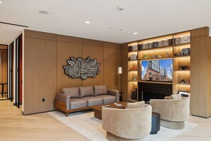 A modern living room with a sofa, armchairs, a coffee table, and a bookshelf with books and decorative items. - Placemakr Buzzard Point (Washington)