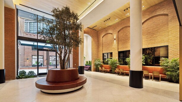 A spacious lobby with a central seating area, large windows, and brick walls. - Placemakr Buzzard Point (Washington)
