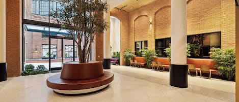 A spacious lobby with a central seating area, large windows, and brick walls.