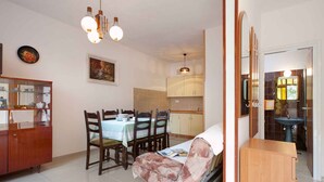 A dining area with a table set for four, a sofa, and a cabinet with glass doors.