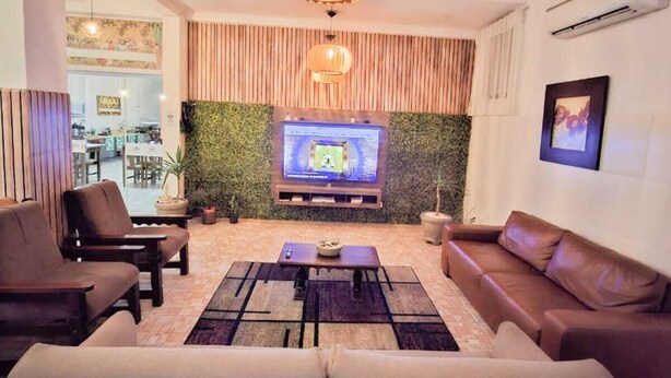 Un salon moderne avec un téléviseur à écran plat, des canapés en cuir et un mur décoratif en bois.
