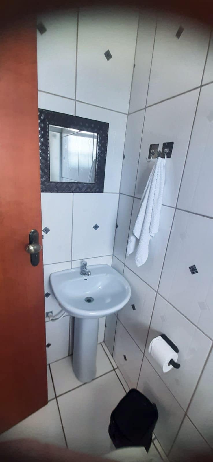 A small bathroom with a white sink, a mirror, and a towel rack.