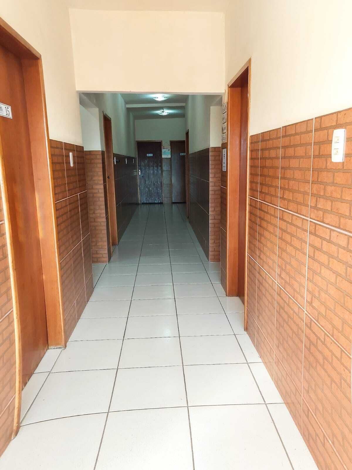 Un couloir avec des carreaux au sol, des portes en bois et des murs en briques.