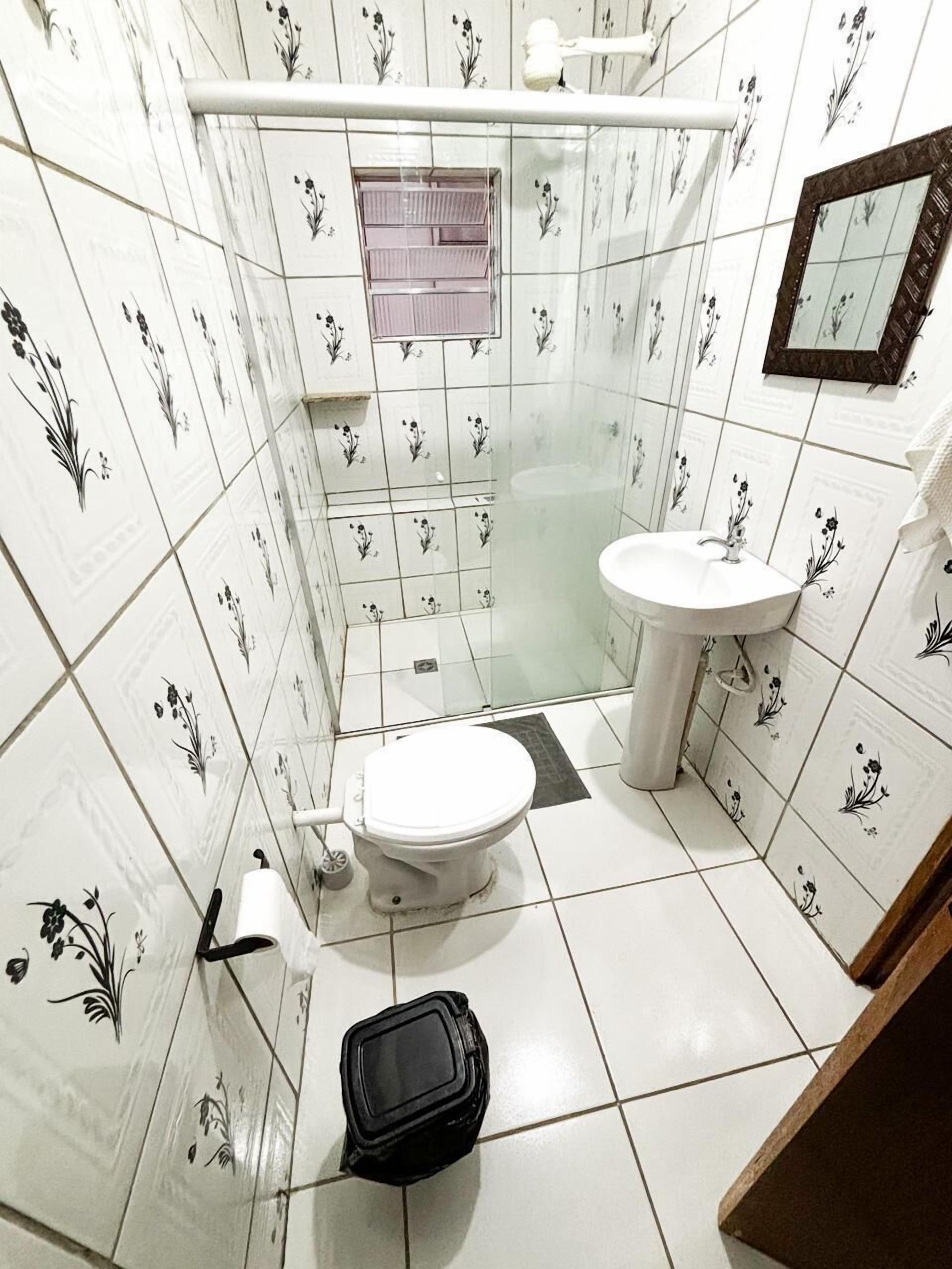 A small bathroom with a toilet, sink, and shower area.