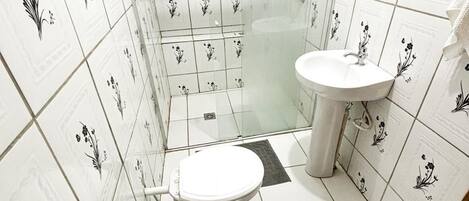 A small bathroom with a toilet, sink, and shower area.