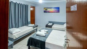 Une chambre d’hôtel avec deux lits simples, un ventilateur de plafond, un tableau au mur et une porte portant un numéro.