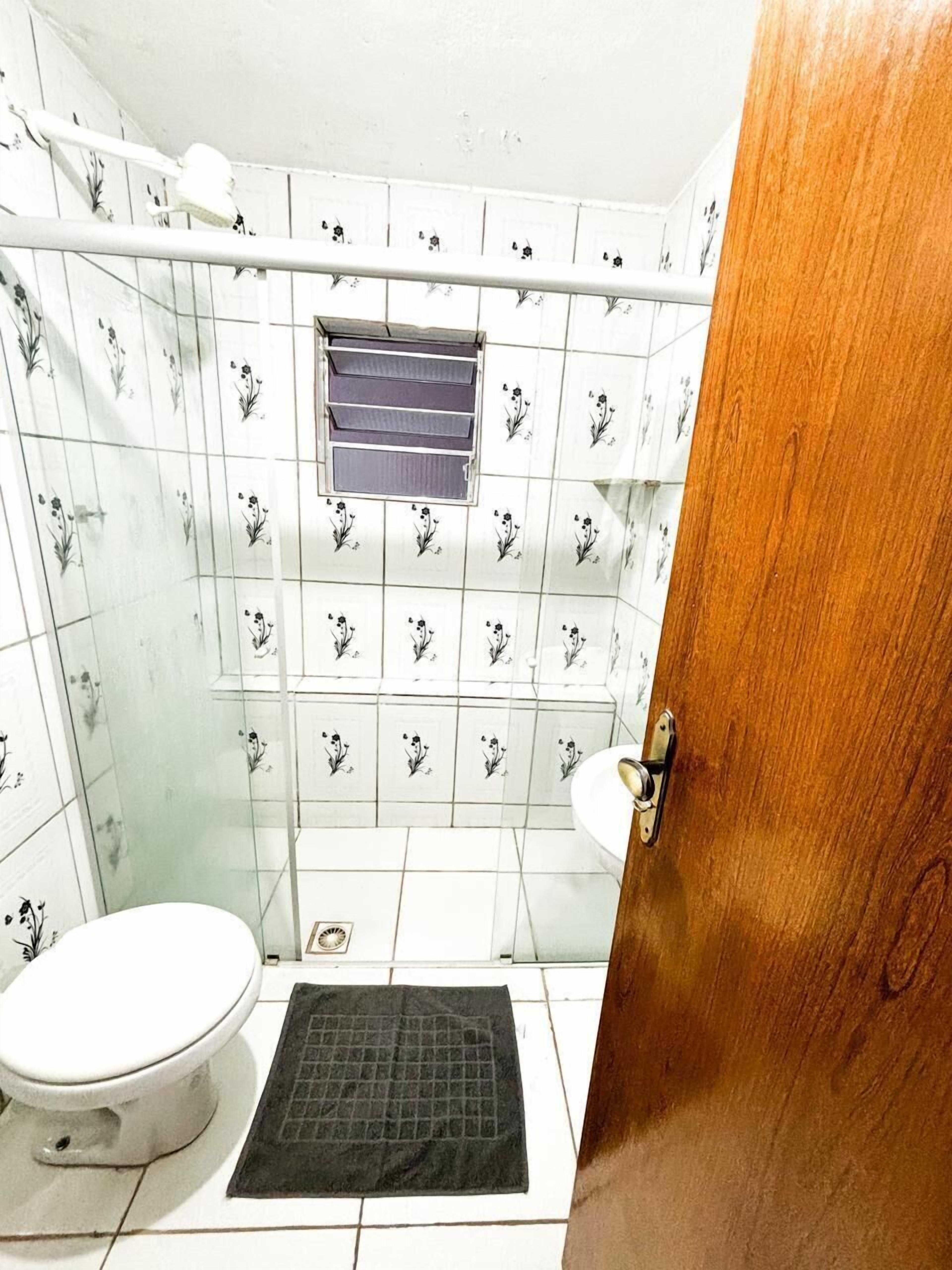 Un baño pequeño con inodoro, zona de ducha y ventana.