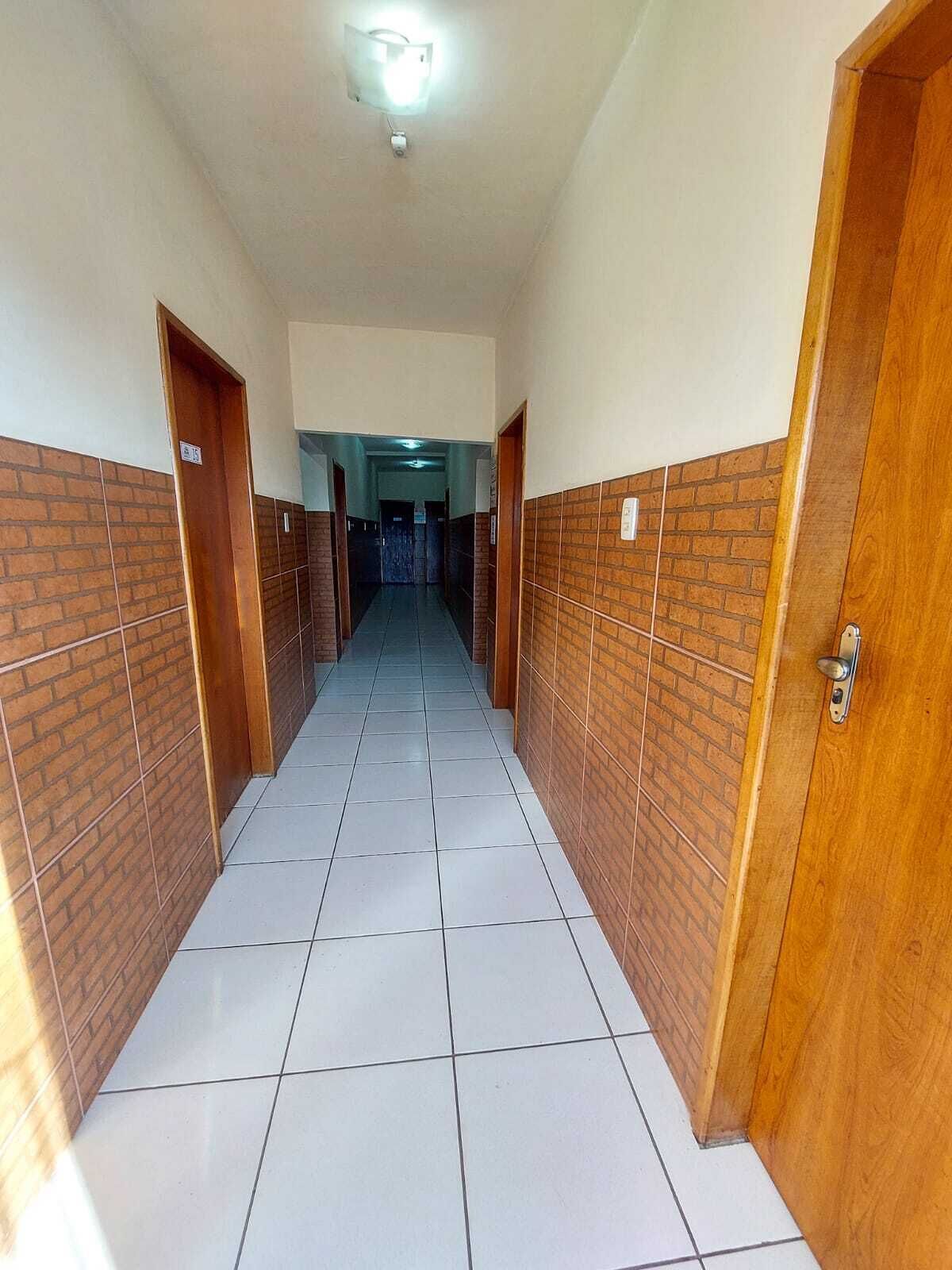 A hallway with tiled floors and brick walls, leading to a door at the end.