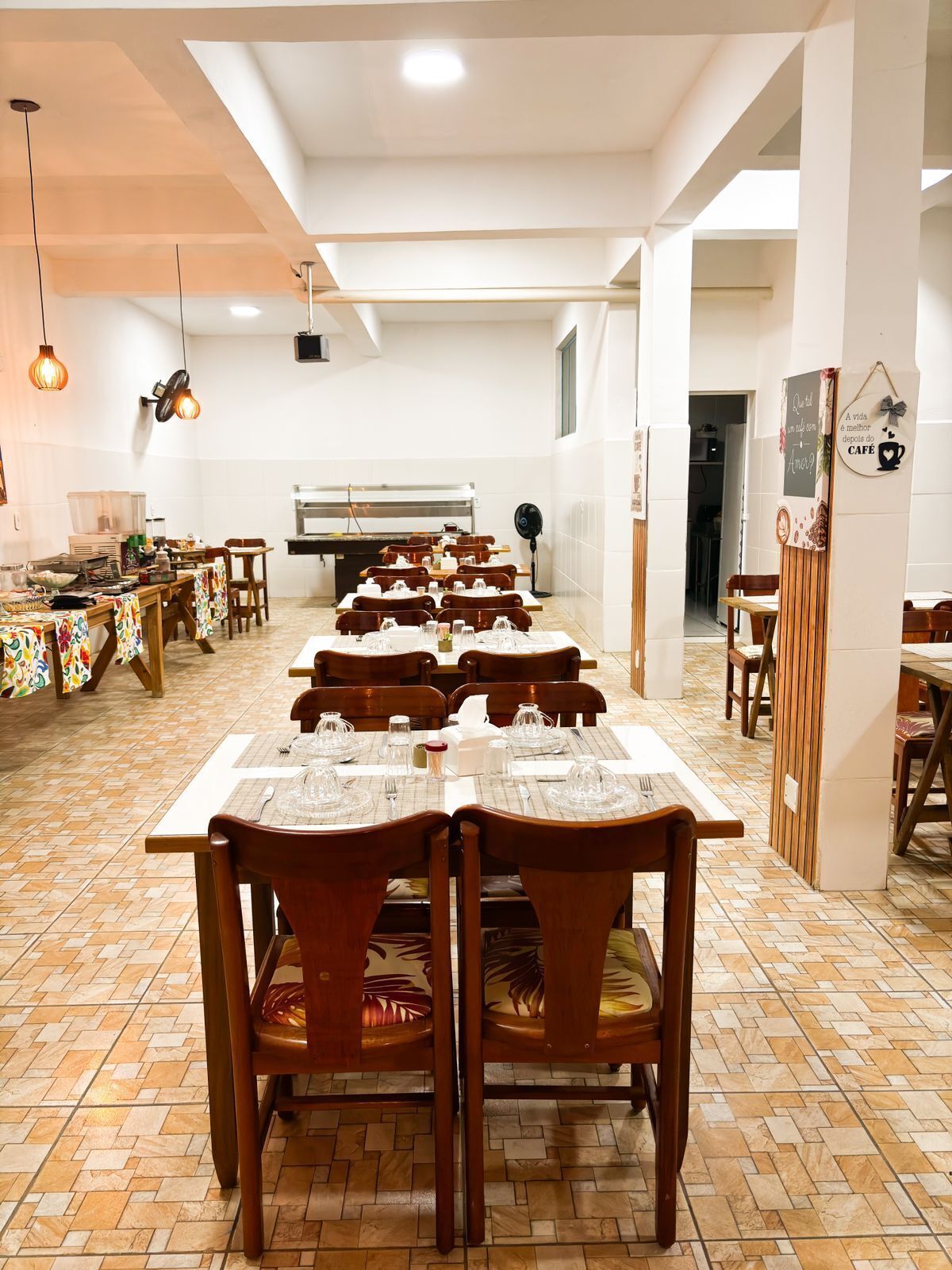 Un comedor con varias mesas y sillas, un piano y una pared con un letrero decorativo.