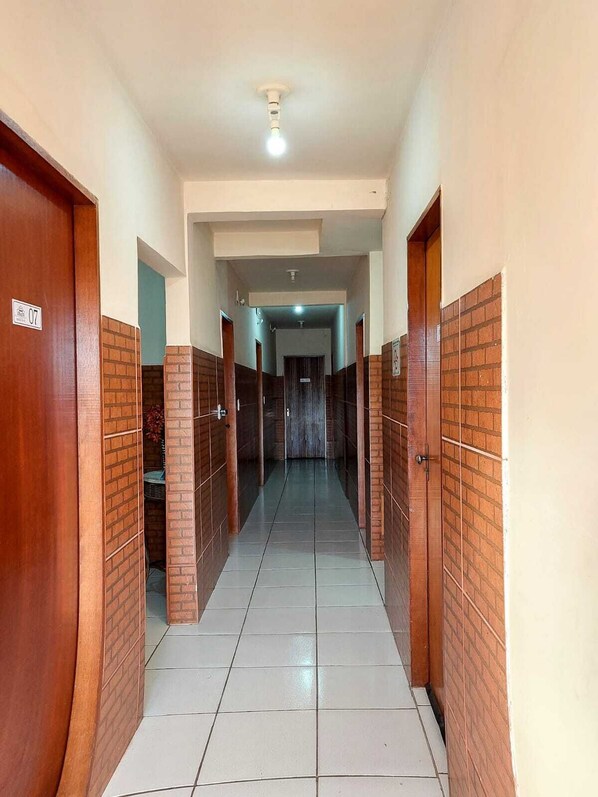 A corridor with tiled flooring, wooden doors, and a ceiling light fixture. - Pousada Parada Da Fe (Aparecida)