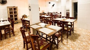 Un vaste espace dédié à la salle à manger, avec de nombreuses tables et chaises, de hauts plafonds et un parquet disposé en motif à chevrons.