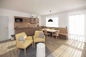 A modern kitchen with built-in appliances, a dining area with wooden furniture, and a large window providing natural light.